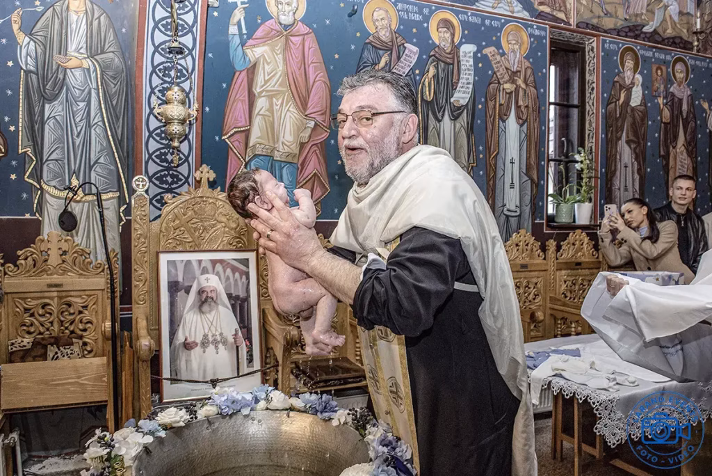 Galerie foto evenimente – ceremonie de botez în biserică, preot și copil în timpul ritualului